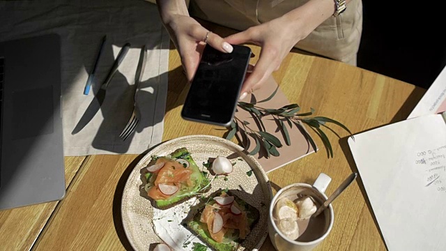 手拿手机拍食物特写。两人早餐:三明治，咖啡，烤面包视频素材