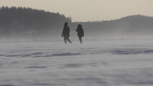 人们在暴风雪中走在湖边视频素材