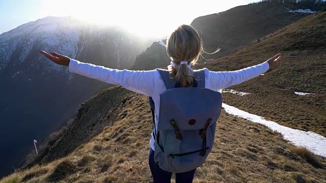 女性徒步旅行者在山顶张开双臂视频素材