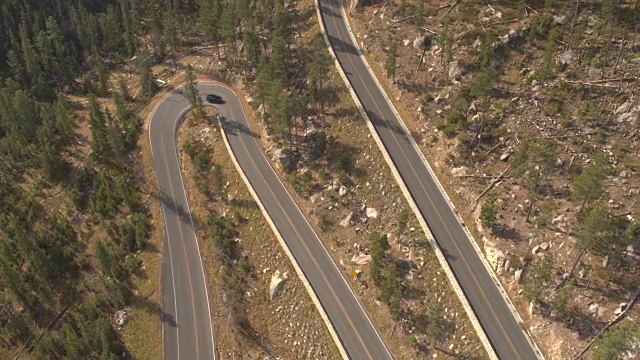 空中汽车沿着蜿蜒的道路行驶，沿着森林覆盖的山口公路视频素材