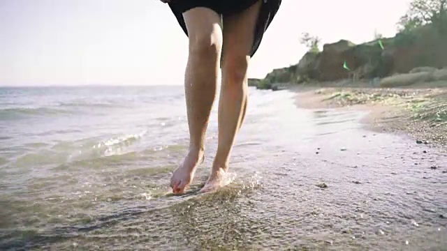 漂亮的微笑的女孩跑在卵石的海滩附近的海水视频素材