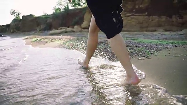 漂亮的微笑的女孩跑在卵石的海滩附近的海水视频素材