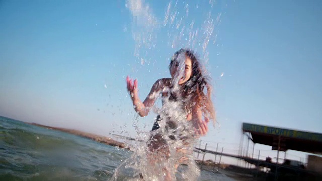 漂亮的年轻女子在海里玩泼水视频素材