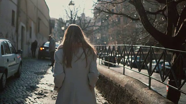 后视图的年轻女子长头发独自走在市中心。女人在路上做梦视频素材