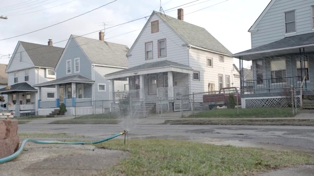 中等角度的两层低层房屋。孩子们在草坪上用软管洒水。住宅区或住宅区视频下载