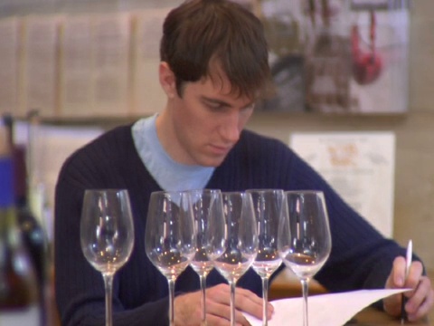 CU, R/F, Man writing in liquor shop, roe wine glasses in foreground, Soho，纽约，美国视频素材