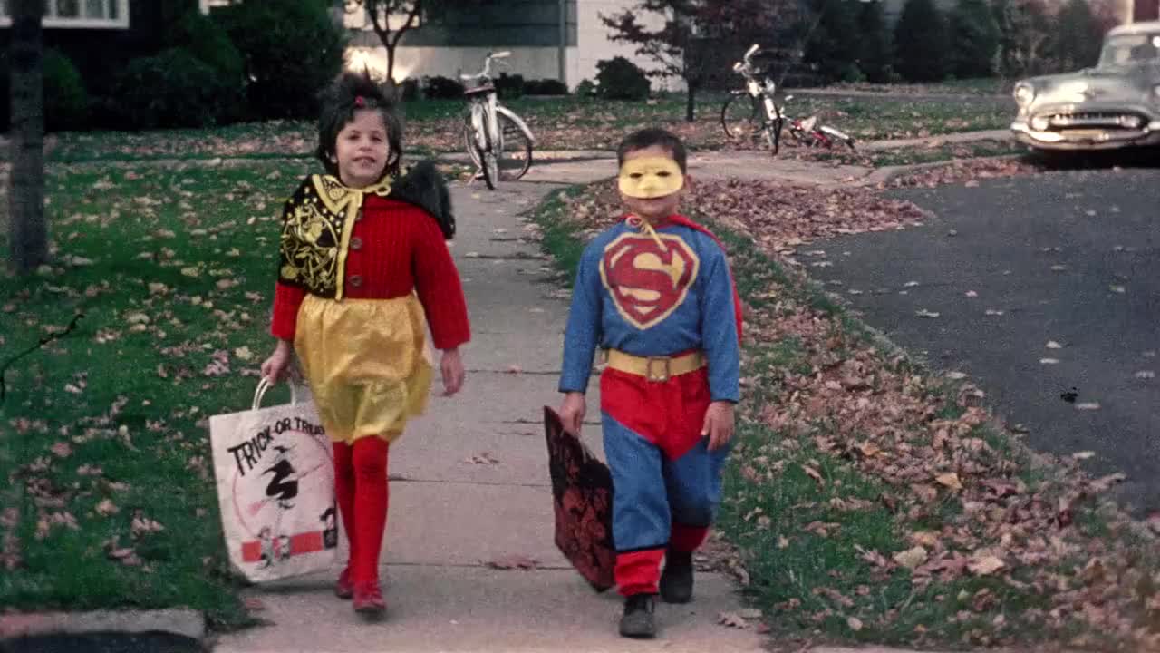 1965年，穿着万圣节服装(男孩穿着超人服装)的大镜头恶作剧者走在人行道上视频素材