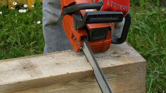 一个工人用汽油锯切割一根木梁视频素材