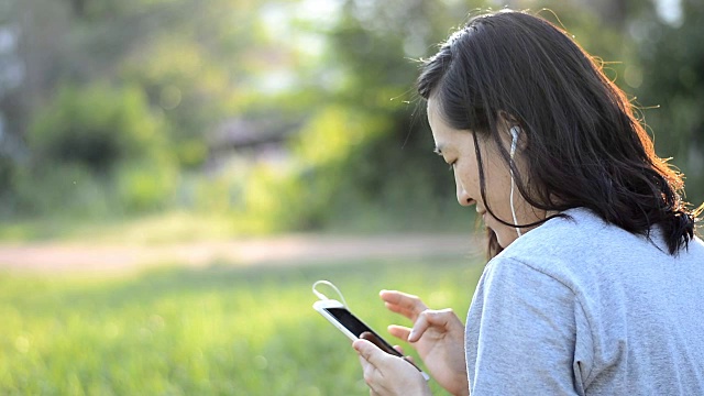 女人喜欢在户外用耳机听音乐视频素材