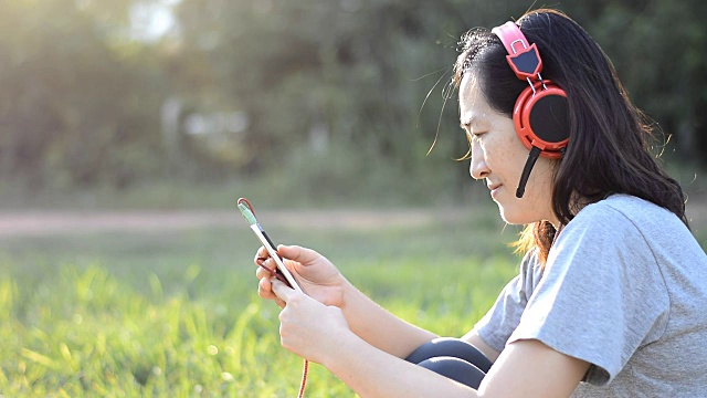 女人喜欢在日落时分用耳机在户外听音乐视频素材