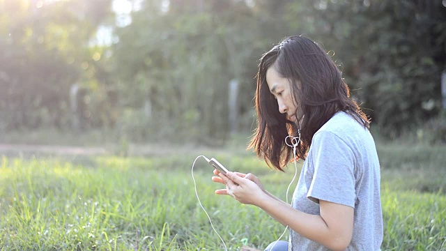 女人喜欢在户外用耳机听音乐视频素材