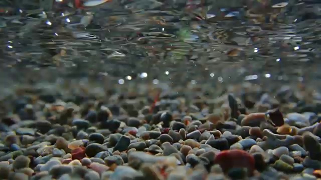 水下拍摄。沙子，沙滩卵石和海浪特写。继续教育视频素材