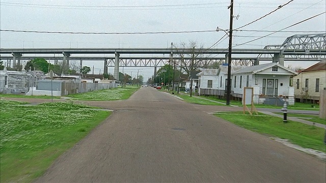 远射后车的视角下行驶在小城镇的道路上，与交通/高速公路立交桥在背景/路易斯安那视频素材