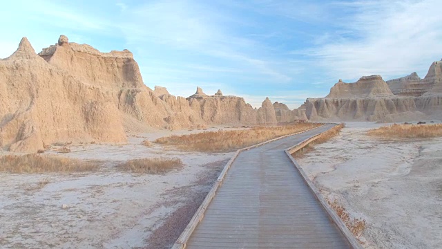 步行穿过Badlands沙漠景观山谷的空木板路视频素材