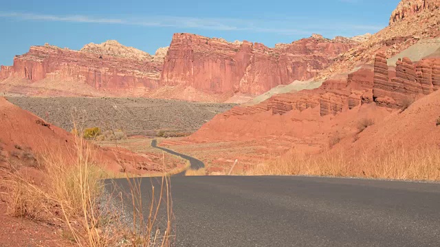 空旷的道路过去侵蚀的山丘和台地山在红色岩石犹他州沙漠视频素材