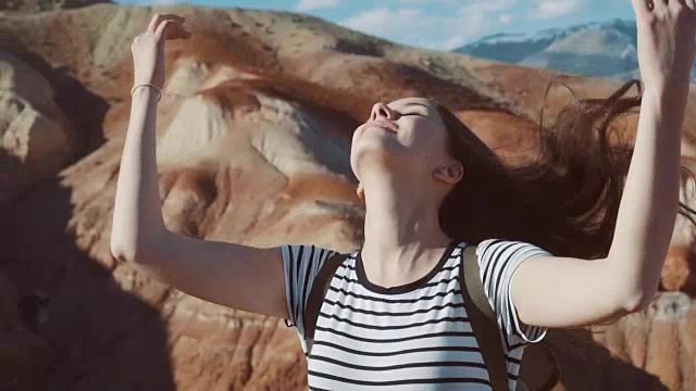 近距离的美丽的年轻女子在自然与棕色的头发在风中吹看山景远足女孩在挪威慢动作视频素材