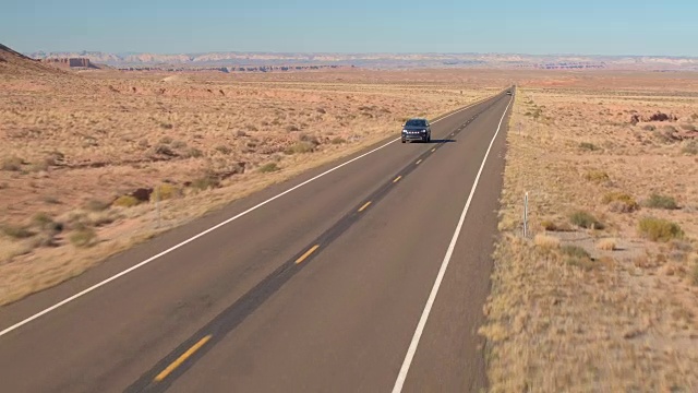 空中的黑色越野车在旅途中驾驶在空旷的道路上通过广阔的沙漠山谷视频素材