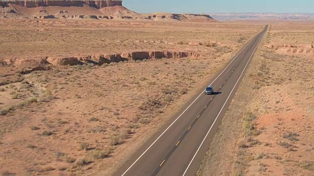 空中的黑色越野车在旅途中驾驶在空旷的道路上通过广阔的沙漠山谷视频素材