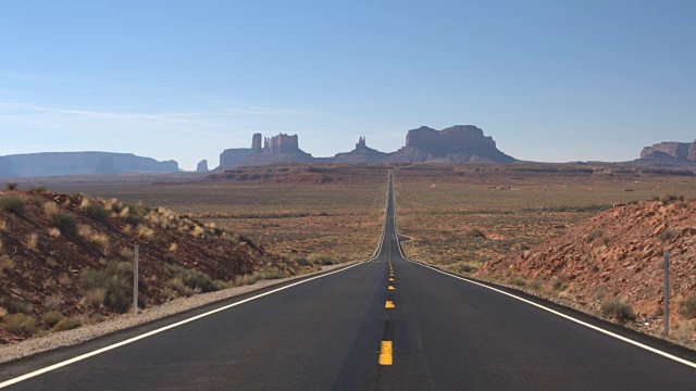 低角度视角:笔直的空道路，通往美国犹他州的标志性纪念碑谷视频素材