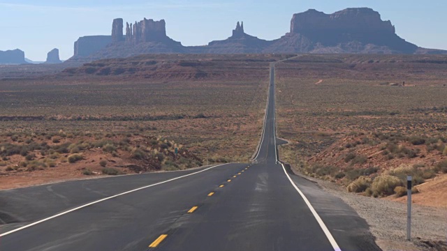 低角度视角:笔直的空道路，通往美国犹他州的标志性纪念碑谷视频素材