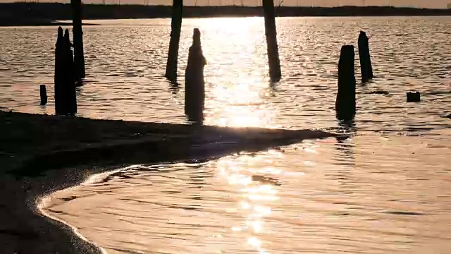 夕阳下金色湖面上的废弃木码头视频素材