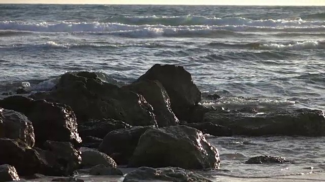 日落时，海浪拍打着岩石视频素材