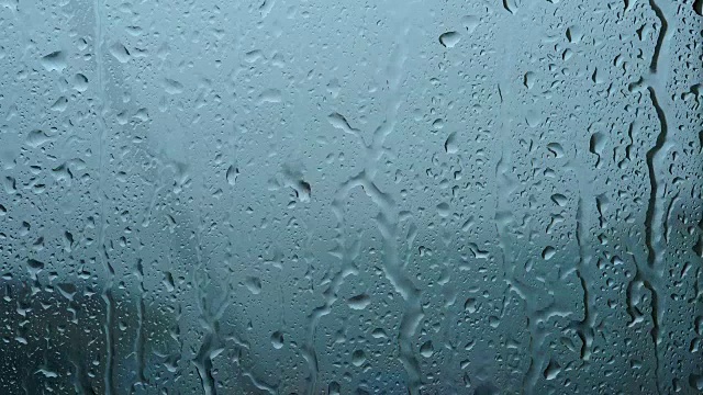 一场大雨带着一阵阵大风从窗户里倾泻而出。溪水迅速地从玻璃杯中流下。夏季飓风伴有瓢泼大雨。视频素材