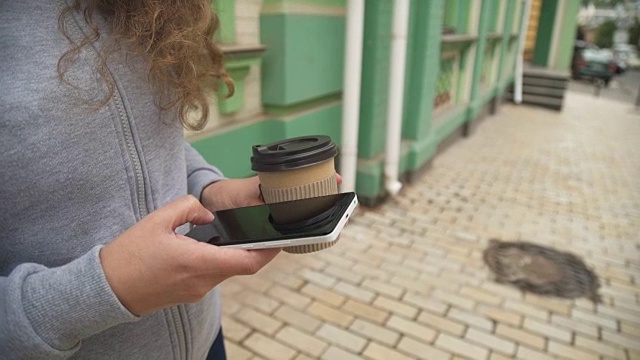 年轻的女商人走在城市街道上喝着咖啡视频素材