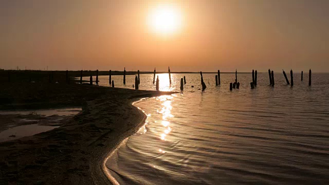 夕阳下金色湖面上的废弃木码头视频素材