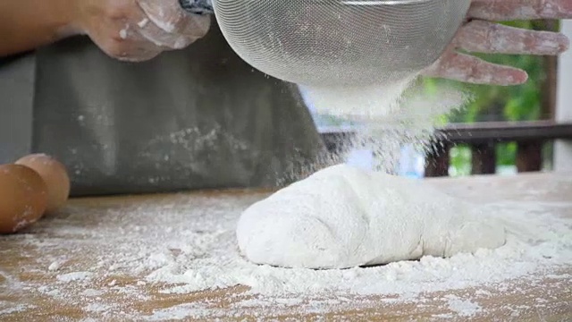 面粉的特写通过金属筛子磨损在自然模糊的背景。配料和准备阶段。Slowmotion拍摄视频素材