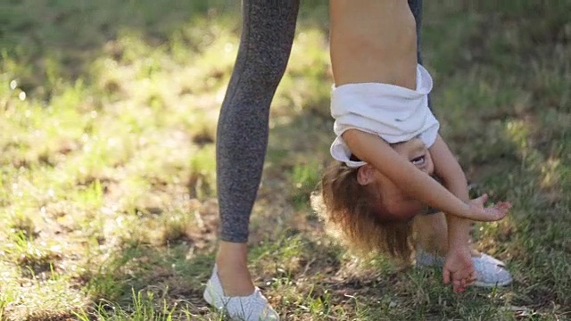 年轻的妈妈和她的小女儿在公园里玩得很开心视频素材