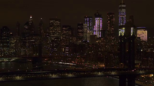 AERIAL:标志性的曼哈顿市中心天际线，两座桥在夜晚点亮视频素材