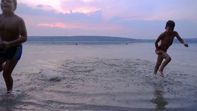 两个男孩从水里奔向夕阳视频素材