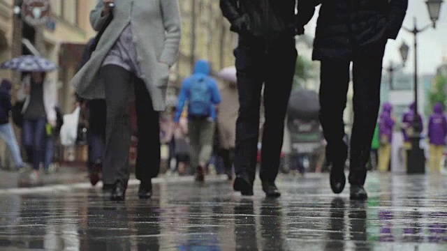 城市街道上的雨天背景。真正的时间。人们在雨中带着雨伞上下班。模糊的散景。自然背景视频素材