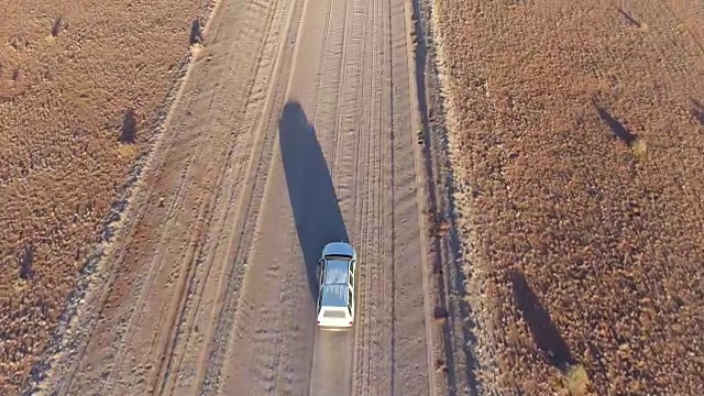 鸟瞰图的旅游车辆行驶在沙砾道路在纳米比亚的沙漠视频素材