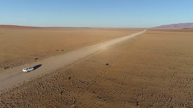 鸟瞰图的旅游车辆行驶在沙砾道路在纳米比亚的沙漠视频素材