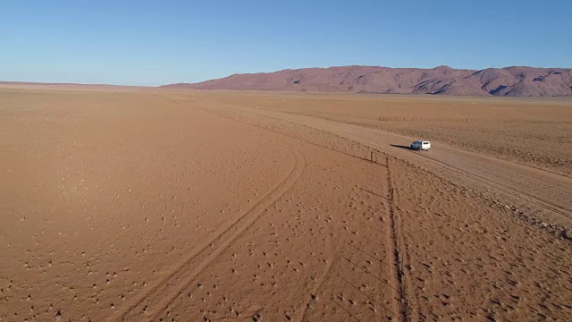 鸟瞰图的旅游车辆行驶在沙砾道路在纳米比亚的沙漠视频素材