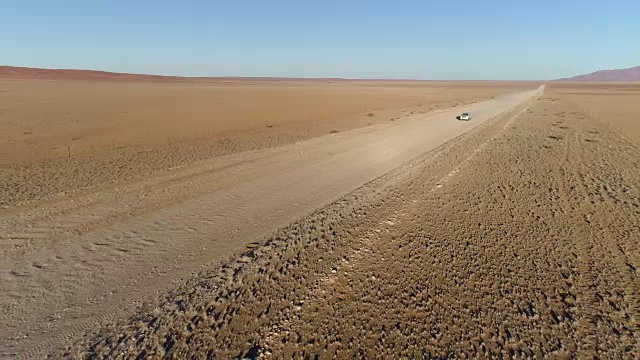 鸟瞰图的旅游车辆行驶在沙砾道路在纳米比亚的沙漠视频素材