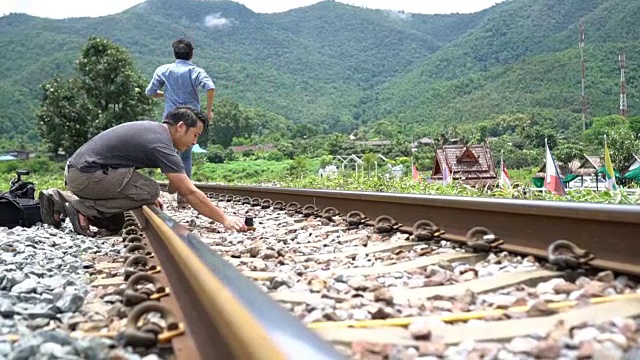 两个亚洲男人在铁路上用他们的相机拍照。视频素材