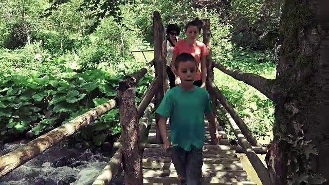 徒步旅行者在热带雨林中的古桥上行走。家庭徒步穿越茂密的热带雨林。健康的年轻运动多种族家庭生活积极的生活方式视频素材