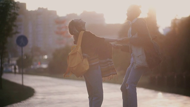 年轻美丽的夫妇在雨中玩耍。快乐的男人和女人转身，亲吻和拥抱在夕阳下视频素材