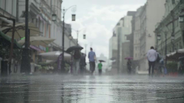 背景大雨天在城市街道。真正的时间。人们在雨中带着雨伞上下班。模糊的散景。自然背景视频素材