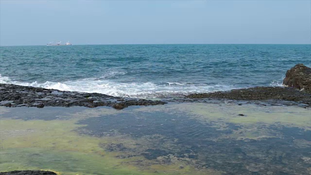 在一个阳光明媚的日子，海浪拍打着岩石视频素材