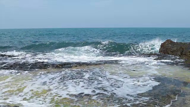 在一个阳光明媚的日子，海浪拍打着岩石视频素材