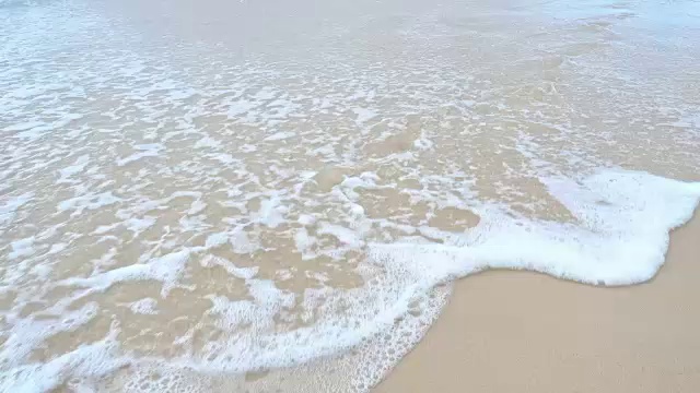 海浪冲击着海岸，抹去了沙滩上的脚印视频素材