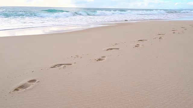 海浪冲击着海岸，抹去了沙滩上的脚印视频素材