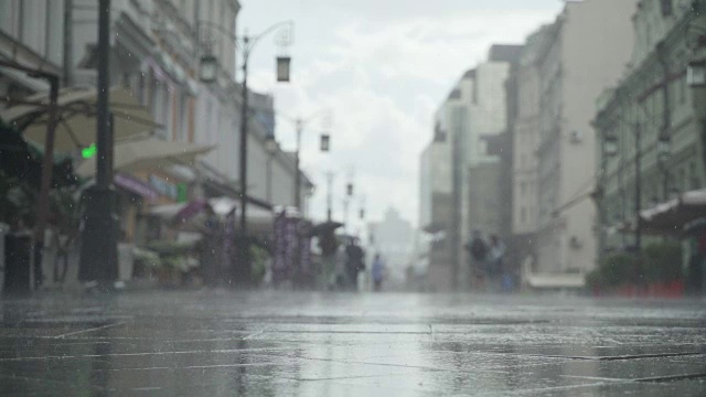 背景大雨天在城市街道。真正的时间。人们在雨中带着雨伞上下班。模糊的散景。自然背景视频素材