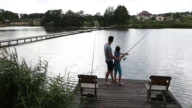 父亲和儿子夏天在宁静的湖边钓鱼视频素材