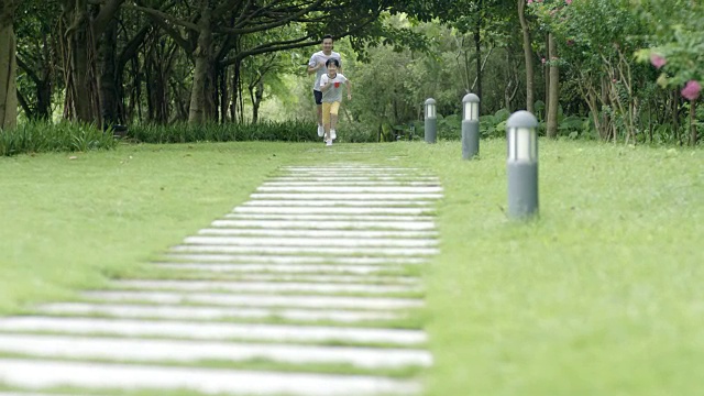 一位亚洲父亲在夏天的公园里跟在儿子后面慢镜头视频素材