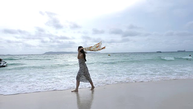 带着围巾在海上漫步的年轻女子视频素材